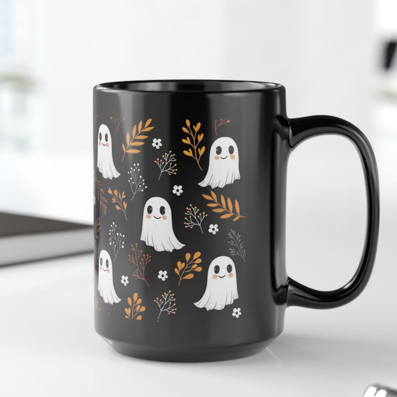 Black mug with happy, smiling ghosts and floral pattern on a black ceramic mug.