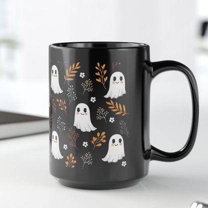 Black mug with happy, smiling ghosts and floral pattern on a black ceramic mug. 