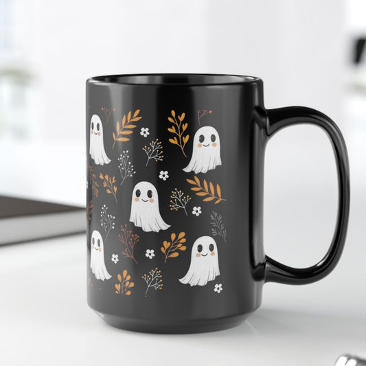 Black mug with happy, smiling ghosts and floral pattern on a black ceramic mug. 